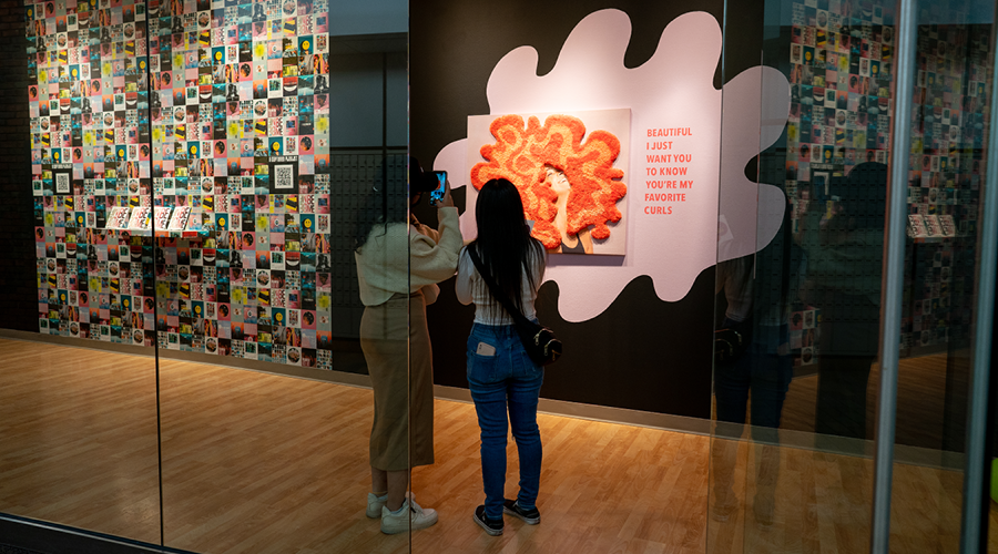 Two people view the artwork in the "To Illuminate Abundance" show in the Christensen Art Gallery on Augsburg's campus.